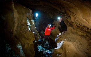 Personer med hodelykt i mørk grotte